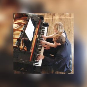 Pianists Oxana Mikhailoff and Vassily Primakov at the piano playing in four hands